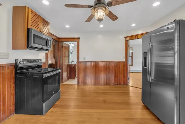 a kitchen with stainless steel appliances granite countertop a refrigerator a stove and a sink with wooden floor
