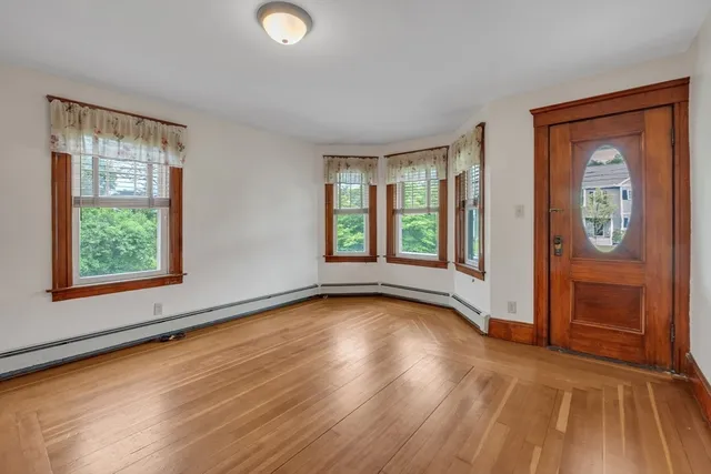 a view of an empty room with window and wooden floor