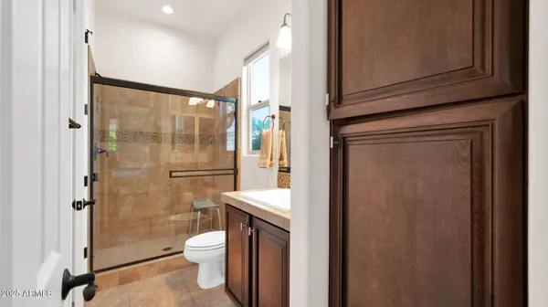a bathroom with a shower sink vanity mirror and toilet