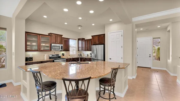 a kitchen with kitchen island granite countertop a stove a sink a dining table and chairs with wooden floor