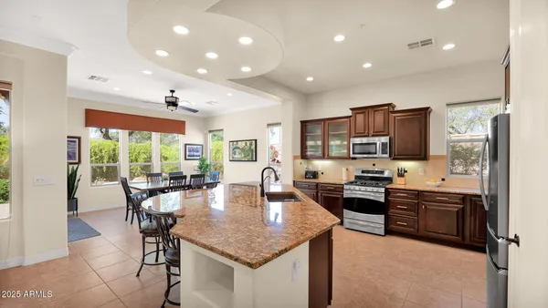 a dining hall with stainless steel appliances granite countertop a stove top oven a sink dishwasher a dining table and chairs with wooden floor