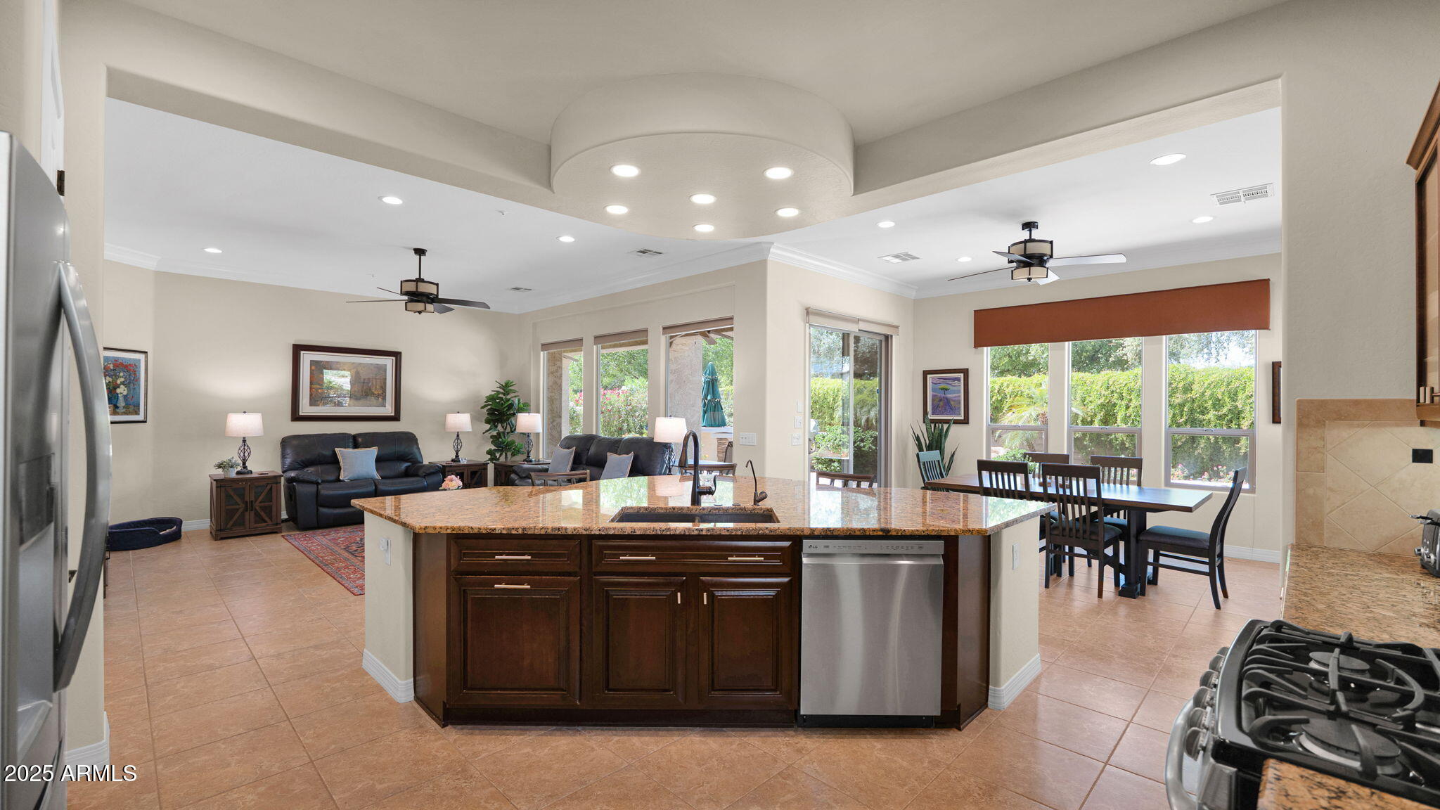 12981 West Yellow Bird Lane Peoria, AZ 85383 - Photo 25 of 47 a dining hall with stainless steel appliances granite countertop a stove top oven a sink dishwasher a dining table and chairs with wooden floor