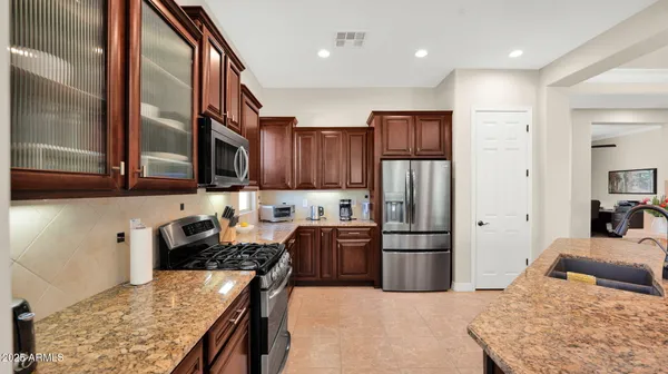 a kitchen with stainless steel appliances kitchen island granite countertop a refrigerator and wooden cabinets