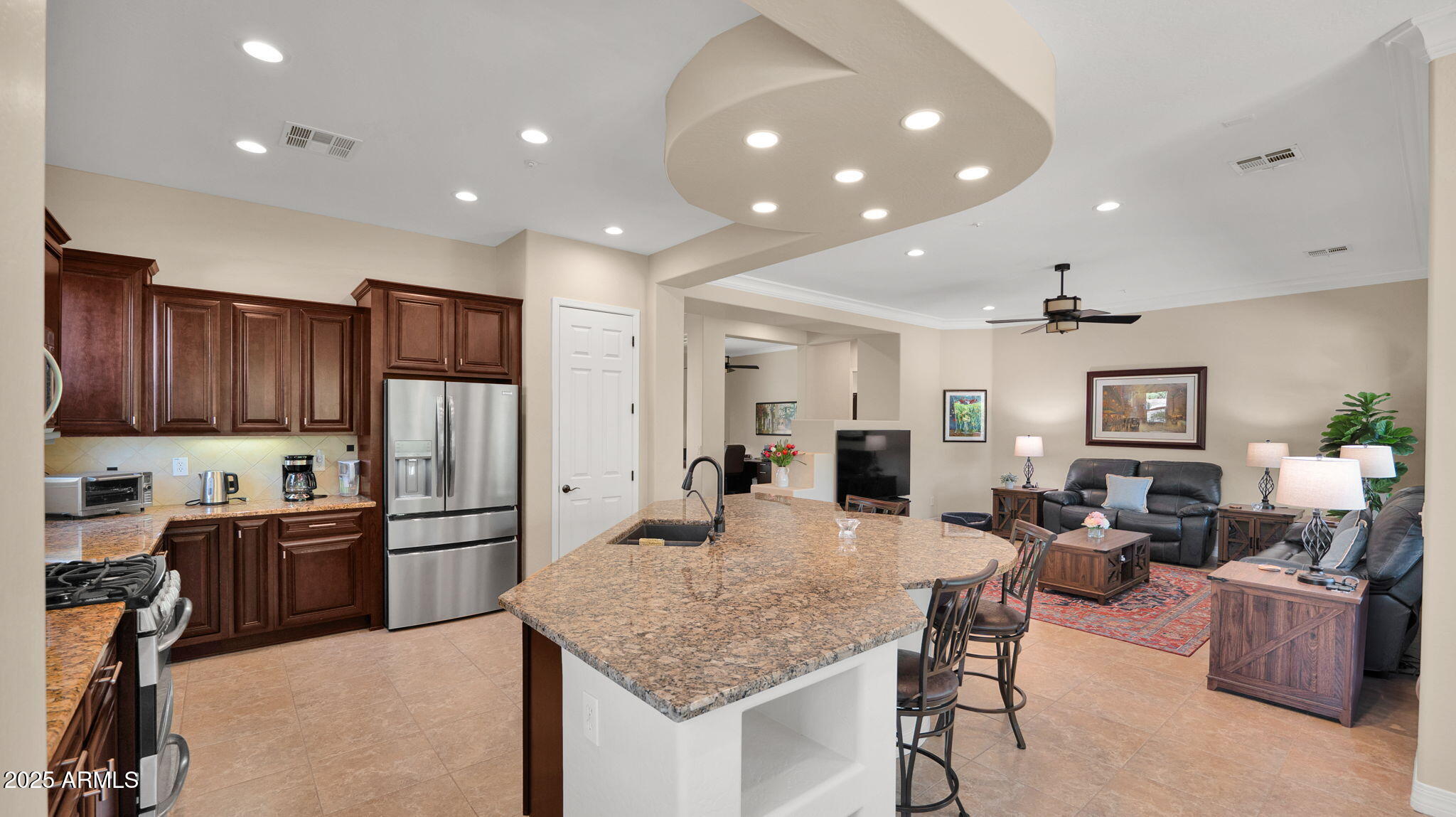12981 West Yellow Bird Lane Peoria, AZ 85383 - Photo 27 of 47 a kitchen with stainless steel appliances kitchen island granite countertop a refrigerator and wooden cabinets
