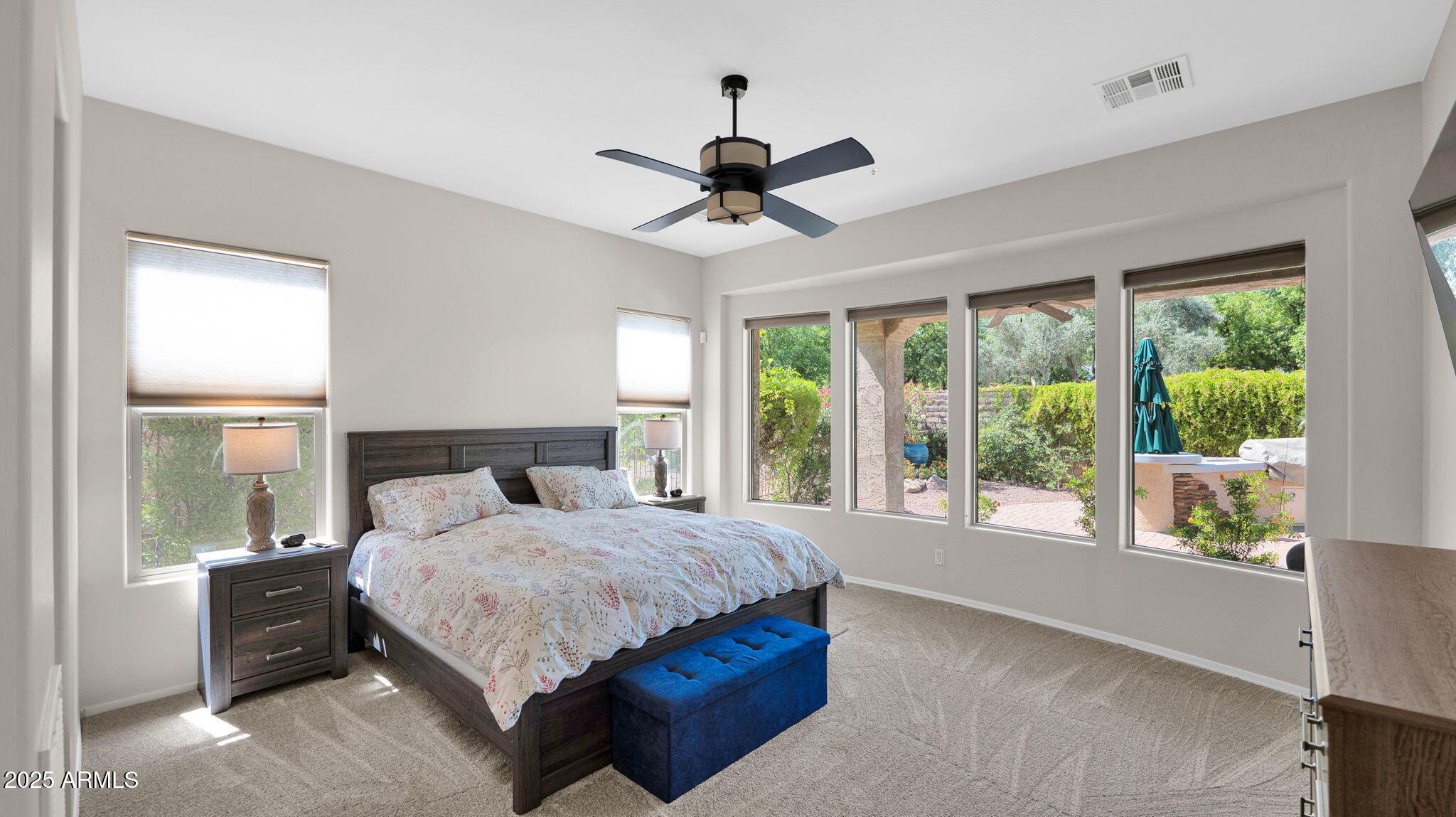 12981 West Yellow Bird Lane Peoria, AZ 85383 - Photo 30 of 47 a bedroom with a large bed large windows and a chandelier