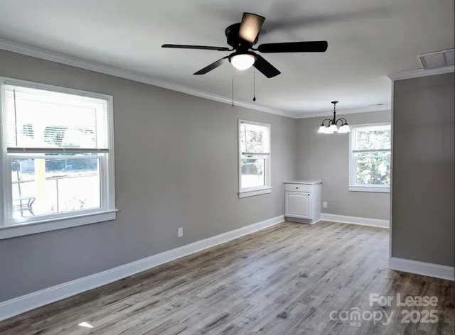 a view of empty room with wooden floor and fan