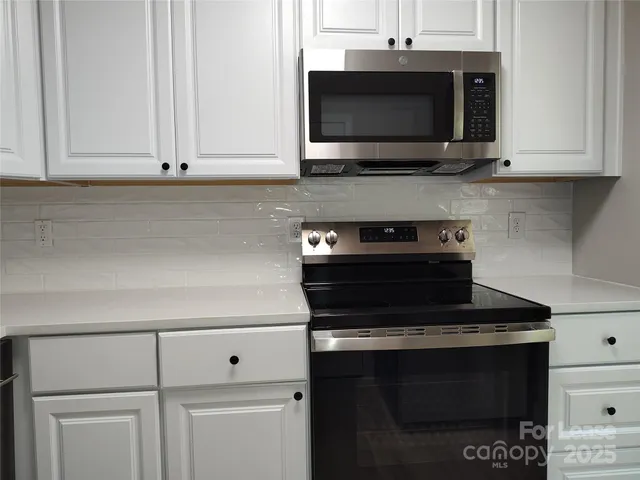 a kitchen with stainless steel appliances granite countertop white cabinets and a stove top oven