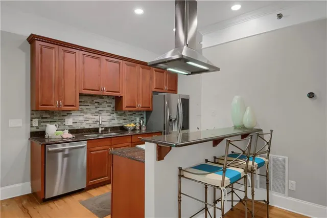 a kitchen with stainless steel appliances granite countertop a sink a stove cabinets dining table and chairs