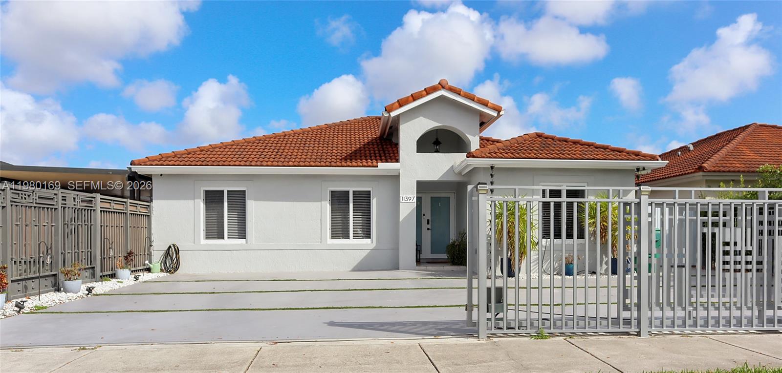 a view of a white house with a small yard and plants