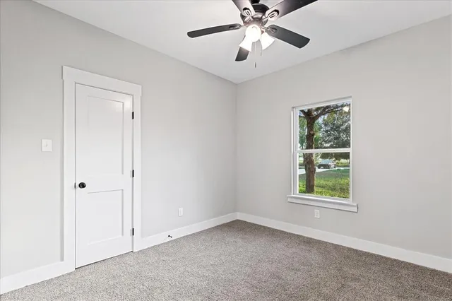 a view of an empty room and chandelier fan
