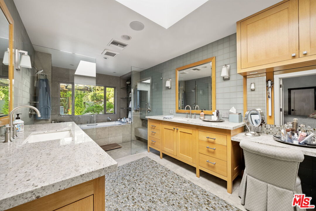 2618 Mandeville Canyon Road Los Angeles, CA 90049 - Photo 19 of 45 a large bathroom with a granite countertop double vanity sink a mirror and a bathtub