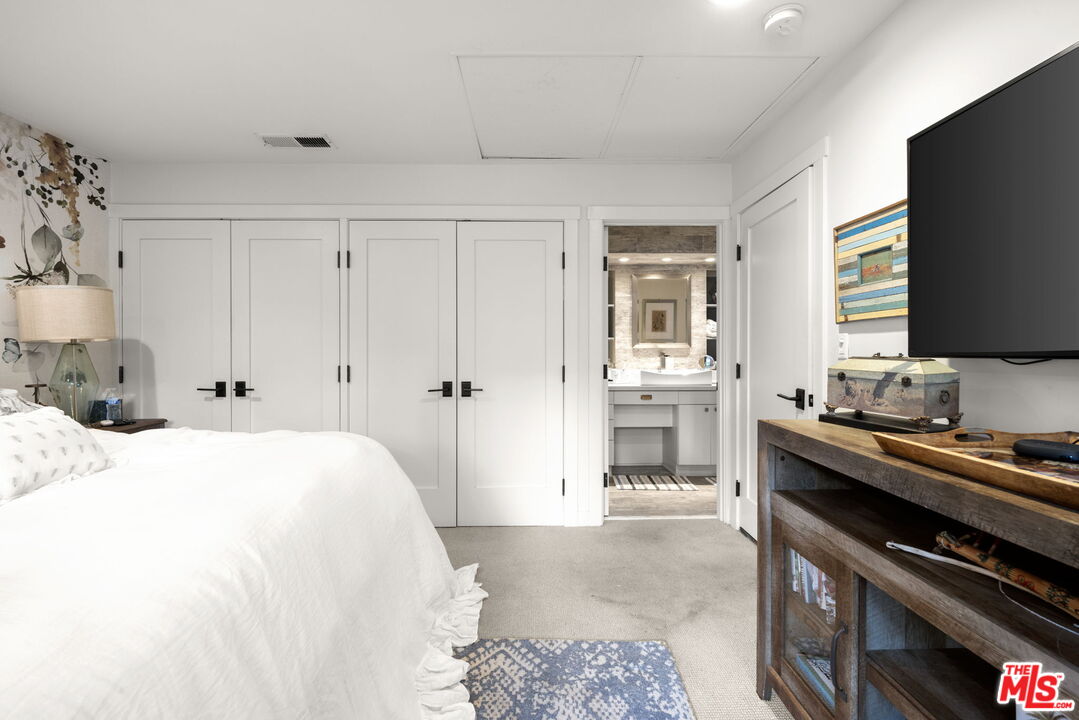 2618 Mandeville Canyon Road Los Angeles, CA 90049 - Photo 23 of 45 a spacious bedroom with a bed and a flat screen tv