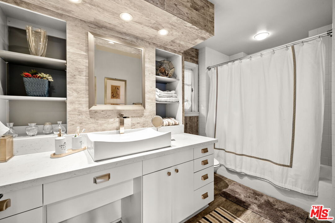 2618 Mandeville Canyon Road Los Angeles, CA 90049 - Photo 24 of 45 a bathroom with a sink a mirror and a shower curtain