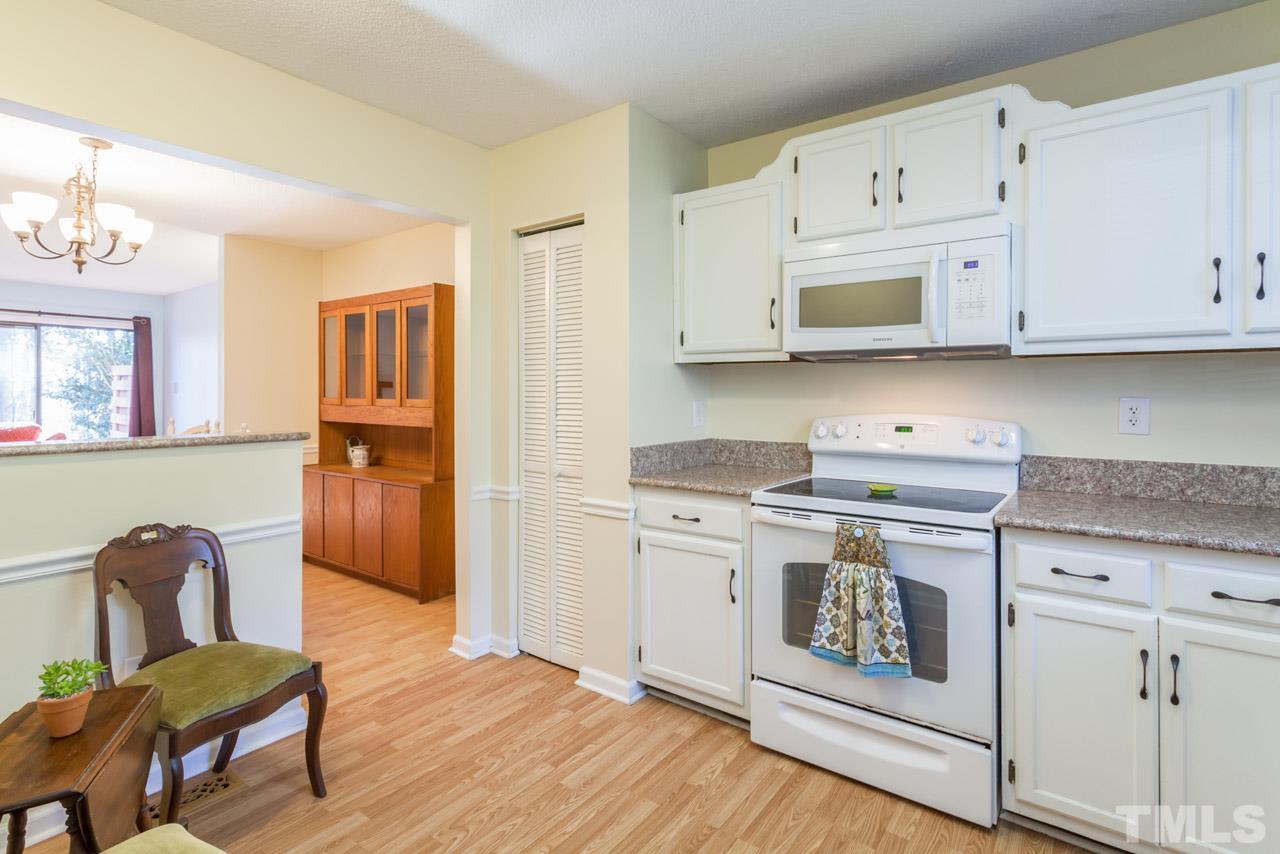 5754 Pool Side Drive Raleigh, NC 27612 - Photo 6 of 23 a kitchen with stainless steel appliances granite countertop a stove a sink dishwasher and white cabinets with wooden floor