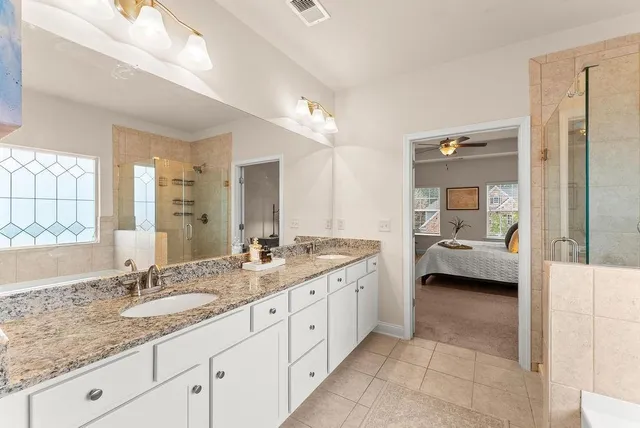 a en suite bathroom with a granite countertop sink and mirror