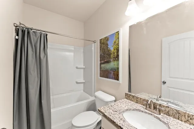 a bathroom with a granite countertop sink toilet and shower