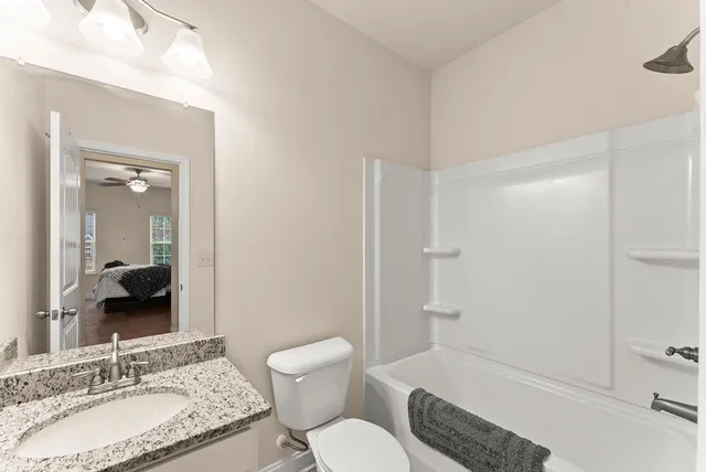 a bathroom with a granite countertop sink toilet a shower and a mirror