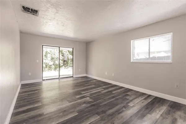 an empty room with wooden floor and windows