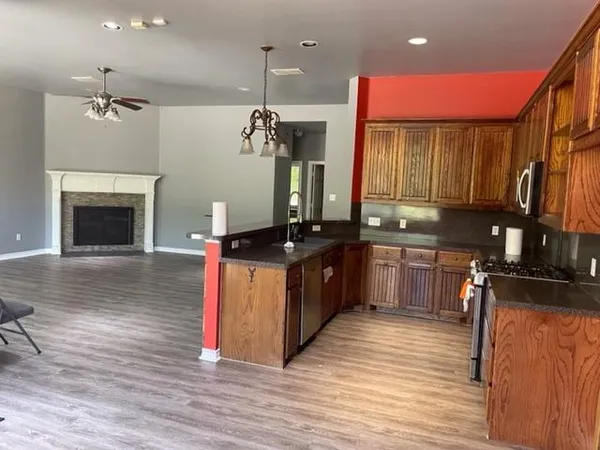 a kitchen with stainless steel appliances granite countertop a refrigerator a sink dishwasher a stove and a wooden floor
