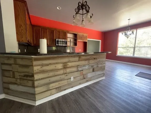 a view of a kitchen with a large window wooden floor and stainless steel appliances