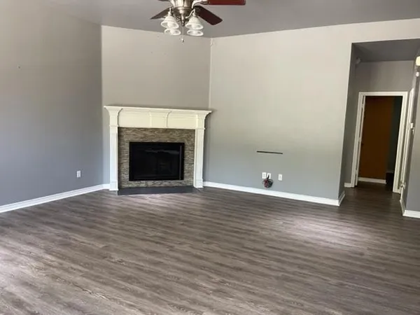a view of an empty room with wooden floor and a fireplace