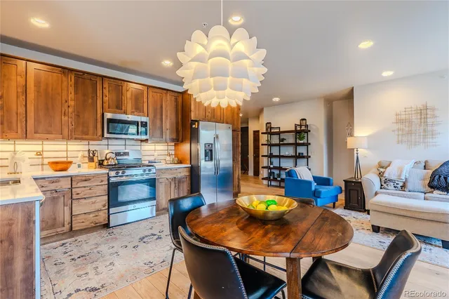 a kitchen with stainless steel appliances granite countertop wooden cabinets a table and chairs