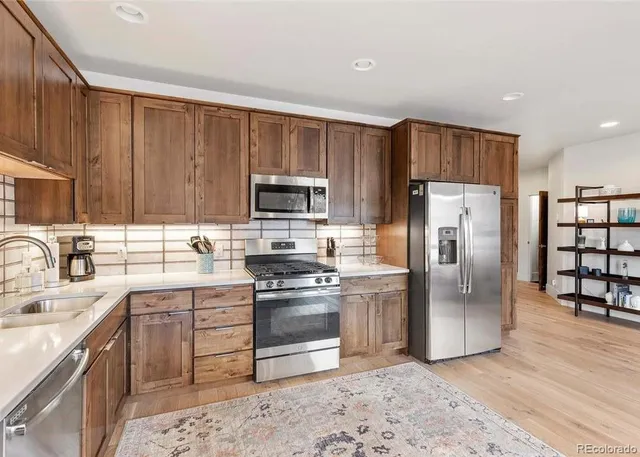 a kitchen with stainless steel appliances granite countertop a refrigerator stove top oven and sink
