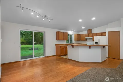 a view of kitchen with stainless steel appliances kitchen island wooden floor and living room view