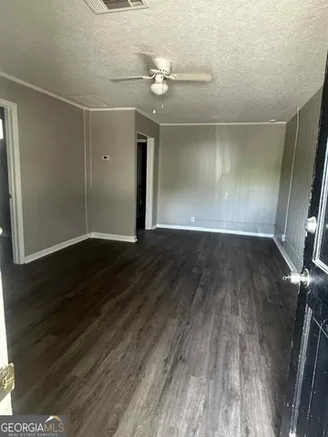 en empty room with wooden floor and fan