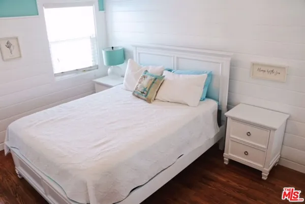 a large white bed in a bedroom next to a window