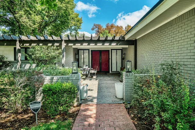 a view of a house with large windows and flower plants