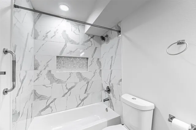 a white toilet sitting next to a bath tub shower