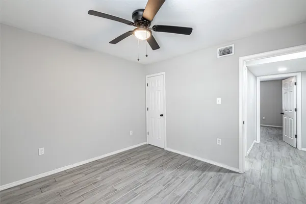 a view of a room with wooden floor and a ceiling fan