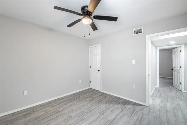 a view of a room with wooden floor and a ceiling fan
