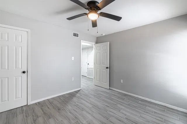 an empty room with wooden floor a ceiling fan and closet