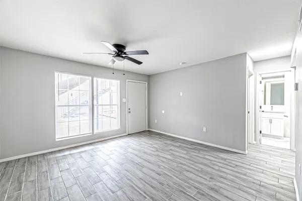 a view of an empty room with a window and wooden floor