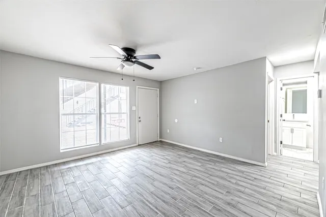 a view of an empty room with a window and wooden floor