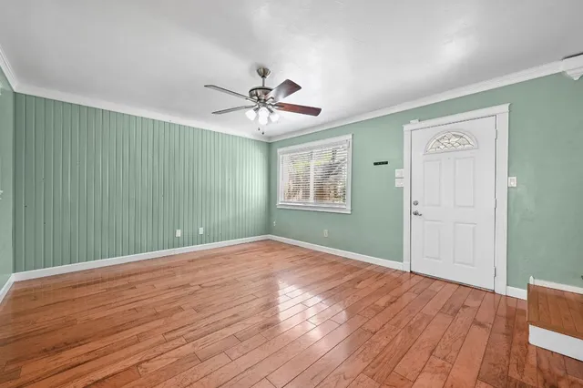 a view of an empty room with a window and wooden floor