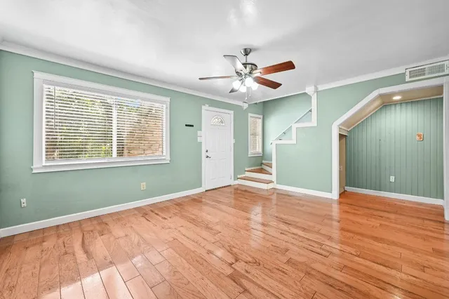 a view of an empty room with window and wooden floor