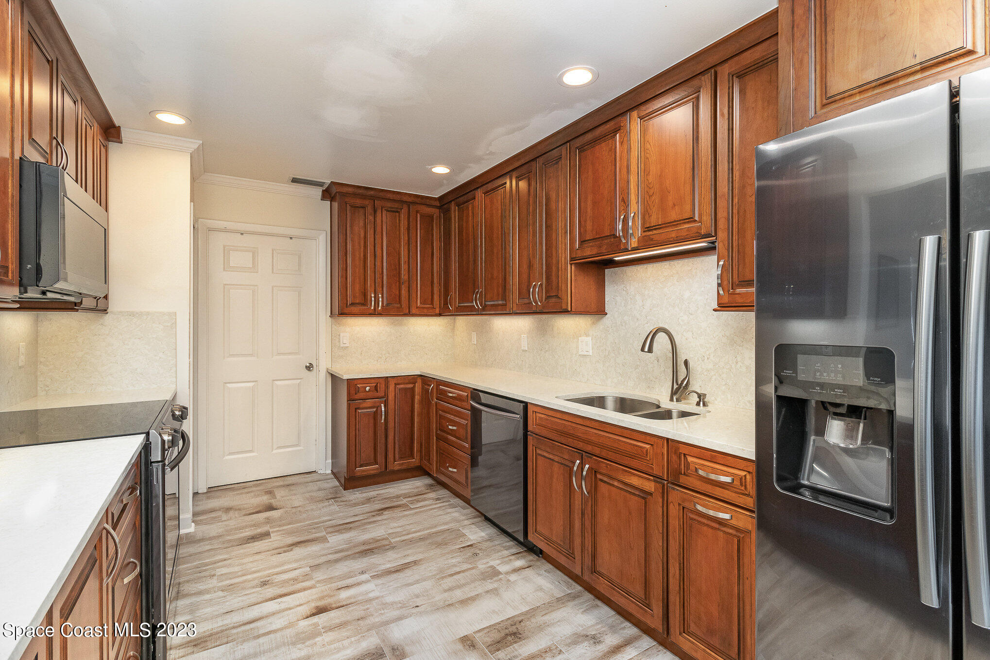 833 Pine Shadows Avenue Rockledge, FL 32955 - Photo 8 of 24 a kitchen with stainless steel appliances granite countertop a refrigerator a sink dishwasher and wooden cabinets with wooden floor