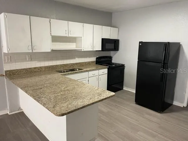 a kitchen with granite countertop a refrigerator and a stove top oven