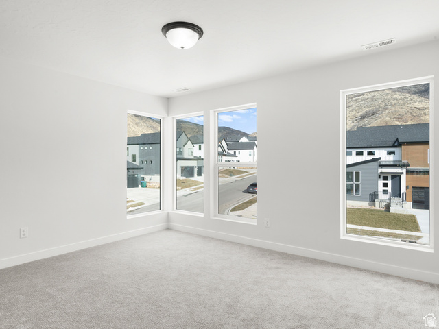 1711 West Canyon Rim Road North Lehi, UT 84048 - Photo 16 of 31 Bright room featuring multiple large windows, light gray carpeting, crisp white walls, and a contemporary flush-mount ceiling light fixture