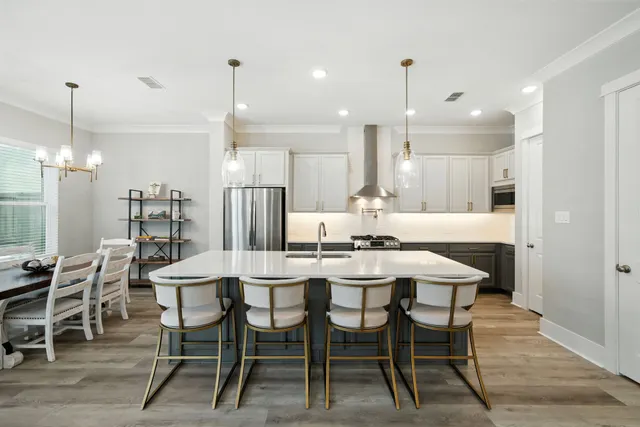 a kitchen with stainless steel appliances a refrigerator a sink a dining table and chairs