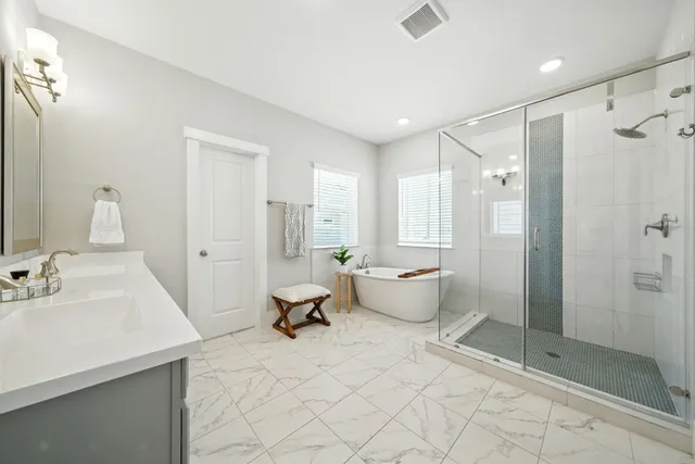 a spacious bedroom with a bed and a flat tv screen on dresser