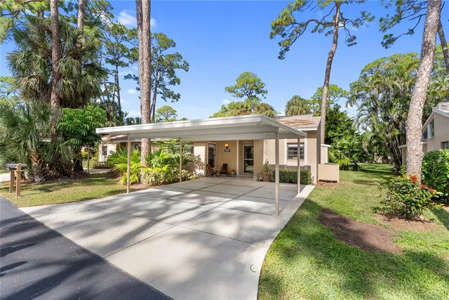 a view of a white house with a yard and table and chairs under an umbrella