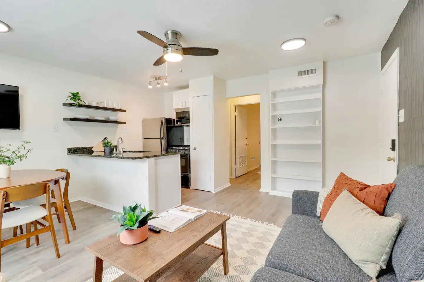 2401 Manor Road, Unit 129 Austin, TX 78722 - Photo 7 of 21 Living room featuring built in shelves, light wood-style flooring, and ceiling fan