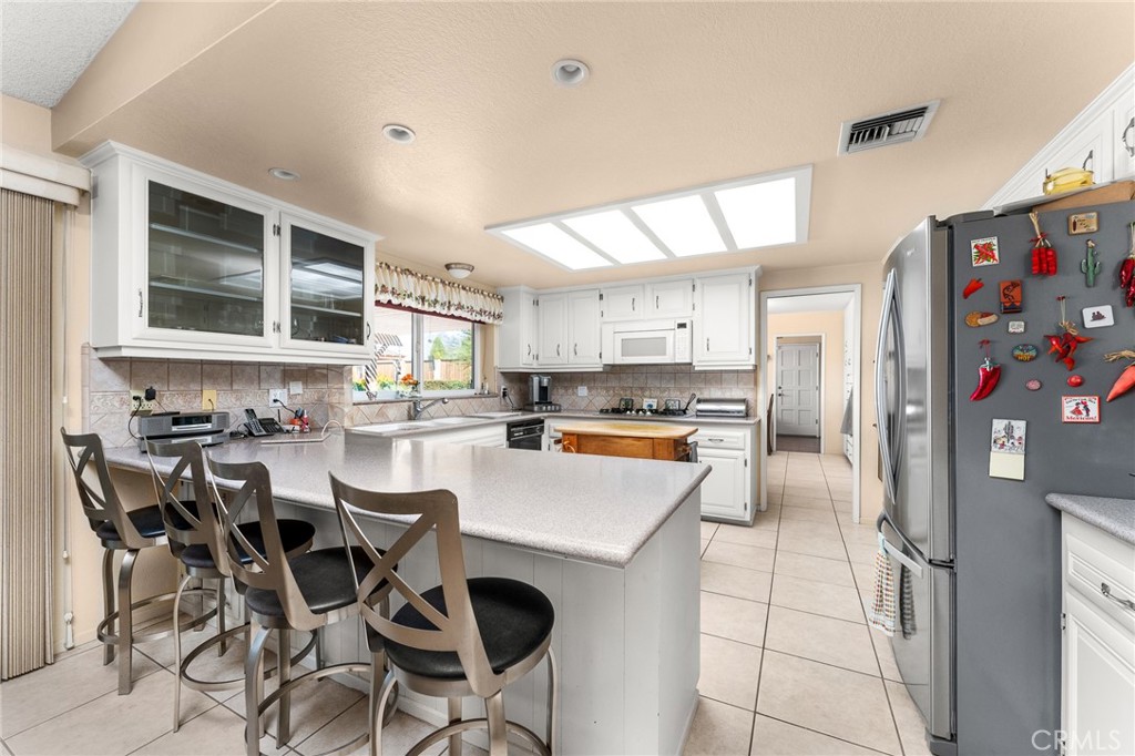 13346 Rimview Court Yucaipa, CA 92399 - Photo 18 of 60 a kitchen with stainless steel appliances kitchen island granite countertop a refrigerator a stove a sink dishwasher and white cabinets with wooden floor