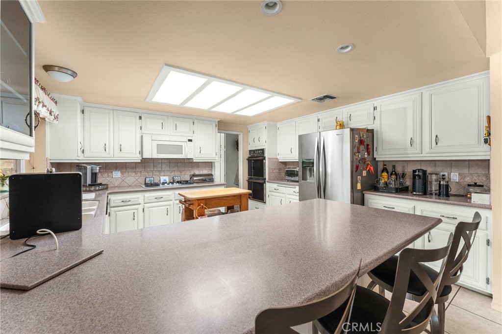 13346 Rimview Court Yucaipa, CA 92399 - Photo 20 of 60 a kitchen with stainless steel appliances granite countertop a stove a refrigerator a sink a stove and white cabinets