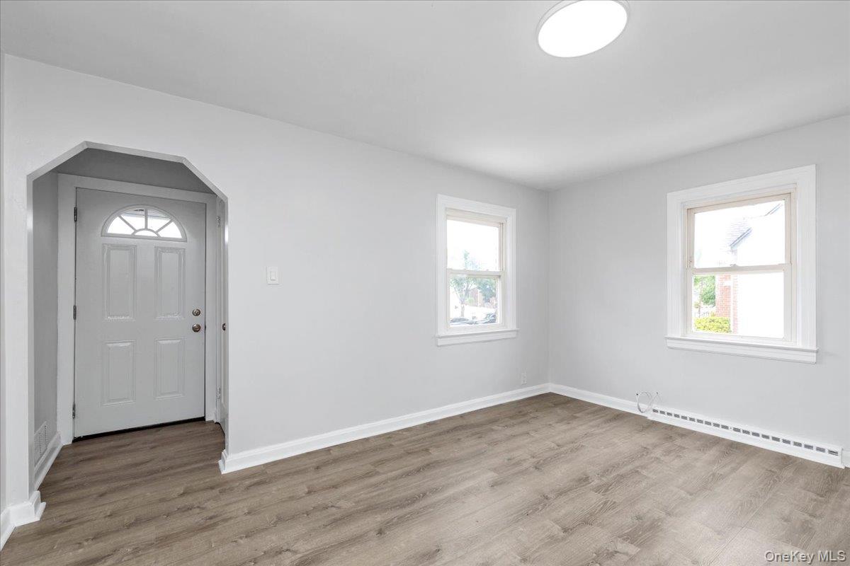 301 Merrifield Avenue Oceanside, NY 11572 - Photo 4 of 16 an empty room with wooden floor and windows