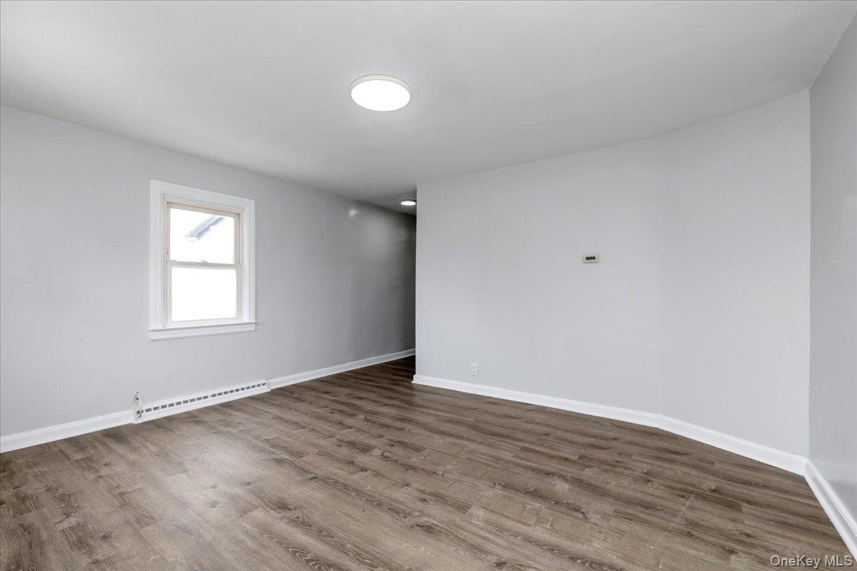 301 Merrifield Avenue Oceanside, NY 11572 - Photo 6 of 16 a view of an empty room with wooden floor and a window